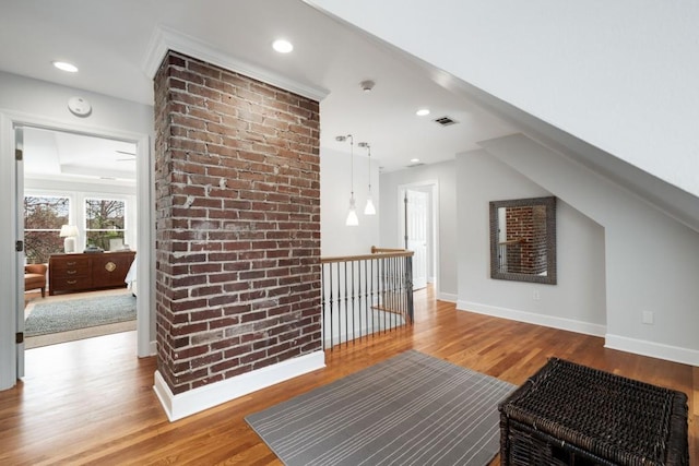 additional living space with visible vents, wood finished floors, recessed lighting, brick wall, and baseboards