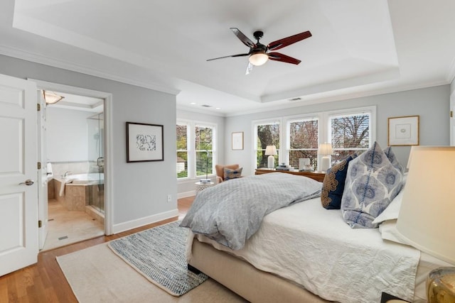 bedroom featuring a tray ceiling, wood finished floors, baseboards, and ornamental molding