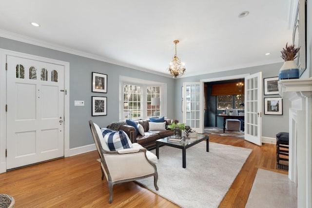 living room with baseboards, a fireplace with flush hearth, ornamental molding, wood finished floors, and a notable chandelier