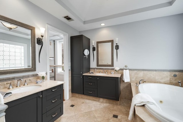 full bath with a sink, visible vents, two vanities, and a tub with jets