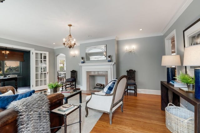 living area featuring baseboards, an inviting chandelier, a fireplace, arched walkways, and light wood-style floors