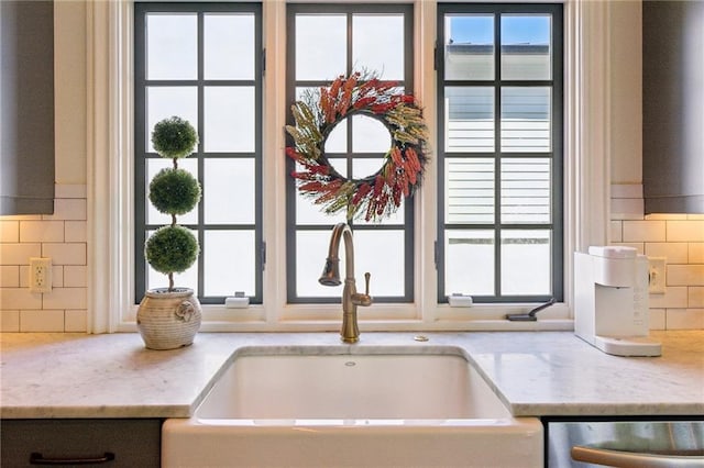 details featuring light stone counters, a sink, backsplash, and dishwasher
