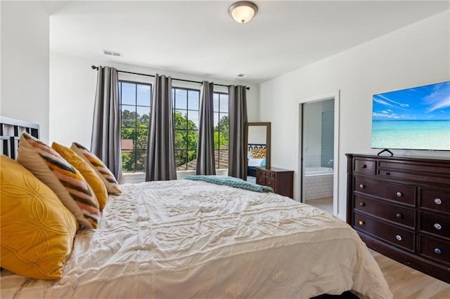 bedroom featuring ensuite bathroom, light wood-style flooring, and visible vents