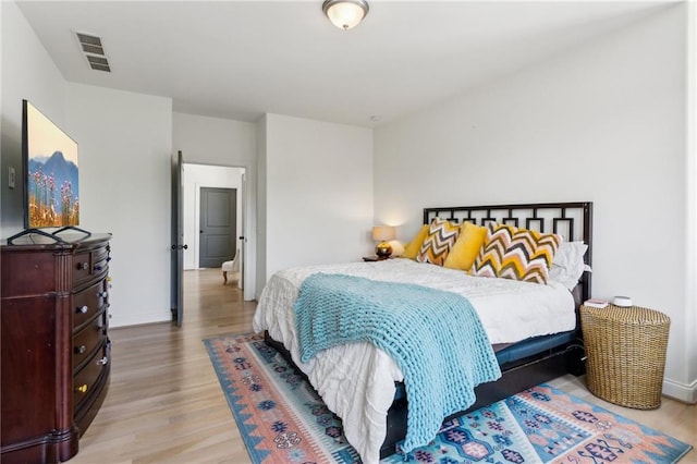 bedroom with baseboards, wood finished floors, and visible vents
