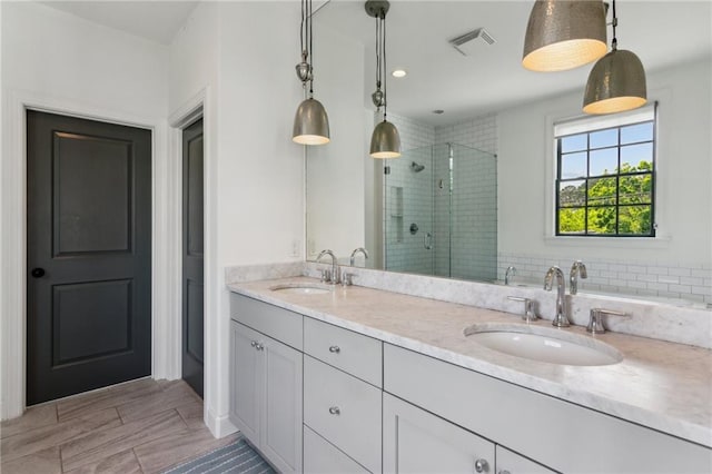 full bathroom with visible vents, a sink, a stall shower, and double vanity