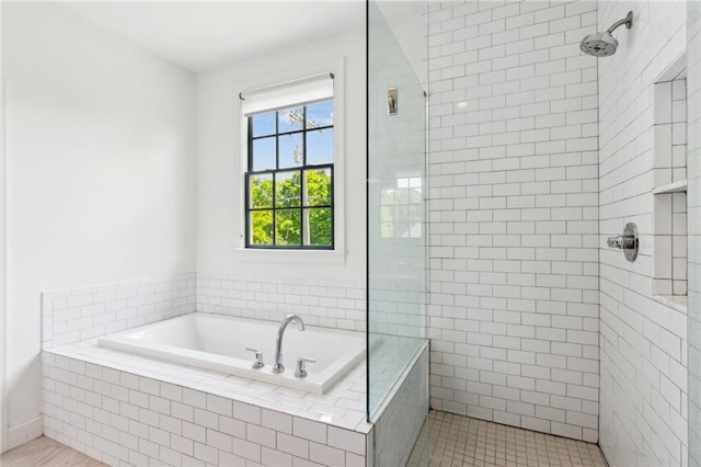 full bathroom with a tile shower and a bath