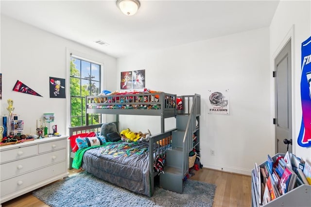bedroom with baseboards, wood finished floors, and visible vents