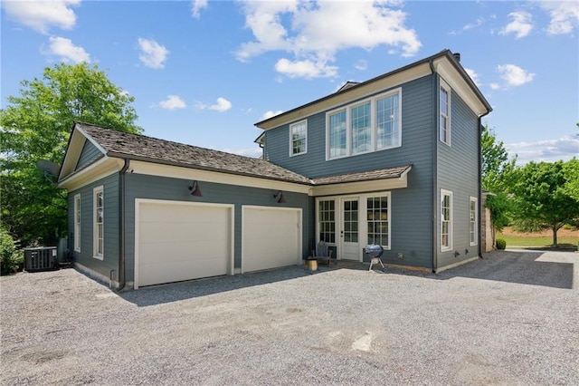 view of front of home featuring central air condition unit, gravel driveway, and a garage