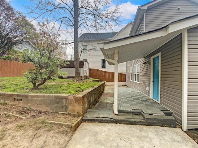 view of side of property featuring a lawn, a patio area, and a storage shed