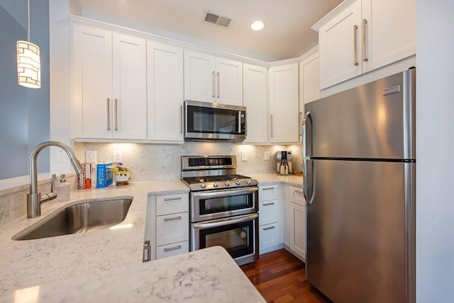 kitchen with stainless steel appliances, visible vents, white cabinetry, and a sink