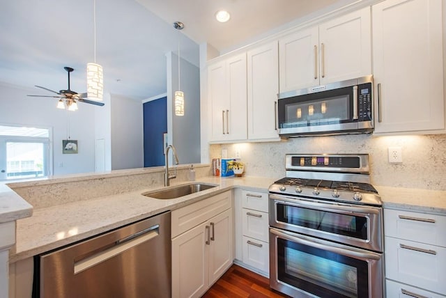 kitchen with appliances with stainless steel finishes, tasteful backsplash, light stone countertops, a sink, and white cabinetry