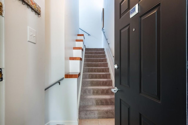 stairway with tile patterned floors and baseboards
