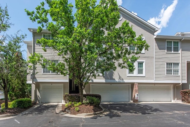 townhome / multi-family property featuring a garage, stucco siding, and driveway