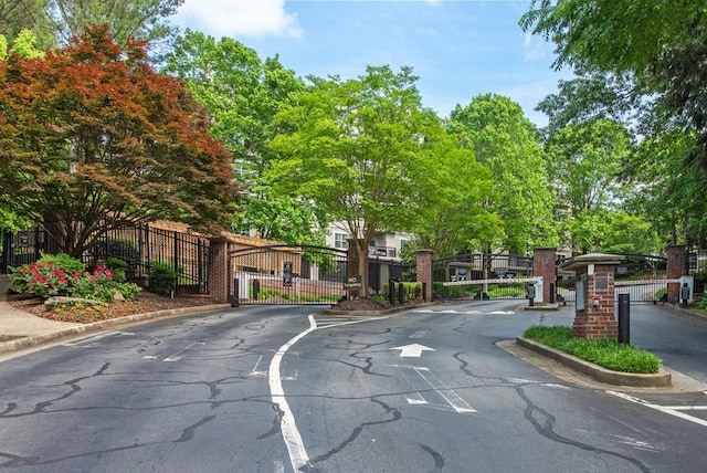view of road with a gate, a gated entry, and curbs