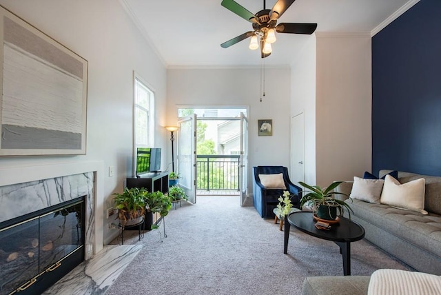 living room featuring crown molding, ceiling fan, a fireplace, and carpet flooring