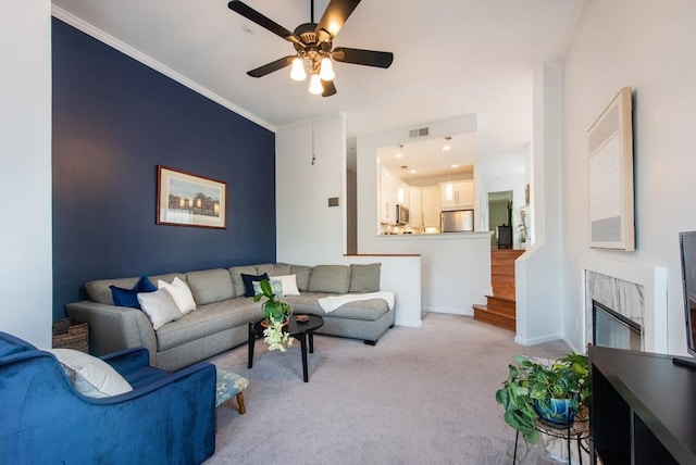 living room featuring ceiling fan, visible vents, light colored carpet, baseboards, and ornamental molding