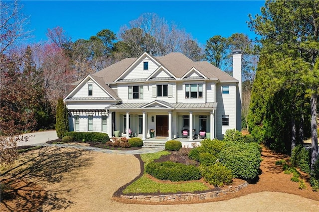 view of front of home with metal roof, a standing seam roof, a chimney, and a porch