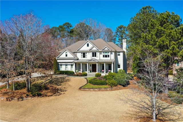 traditional home featuring a chimney, a porch, a standing seam roof, metal roof, and driveway