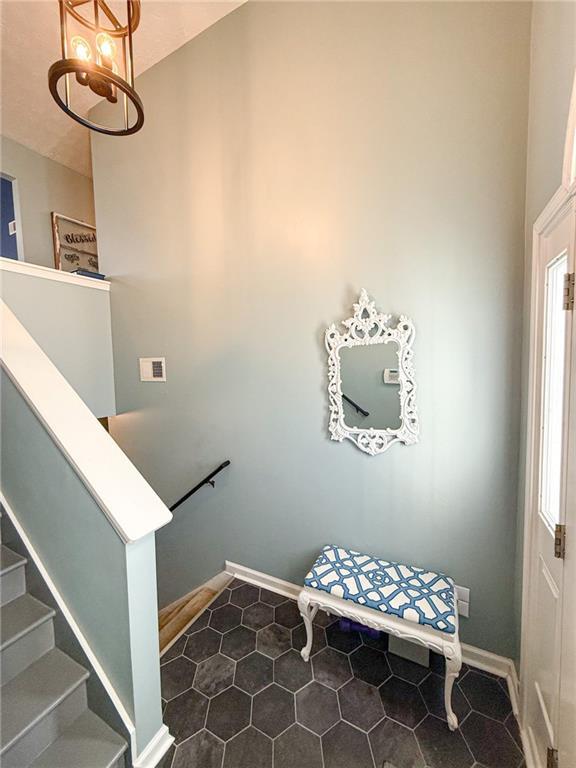 staircase with an inviting chandelier and baseboards