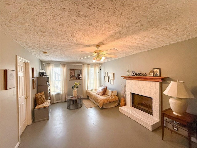 living area featuring ceiling fan, a textured ceiling, a fireplace, and finished concrete floors