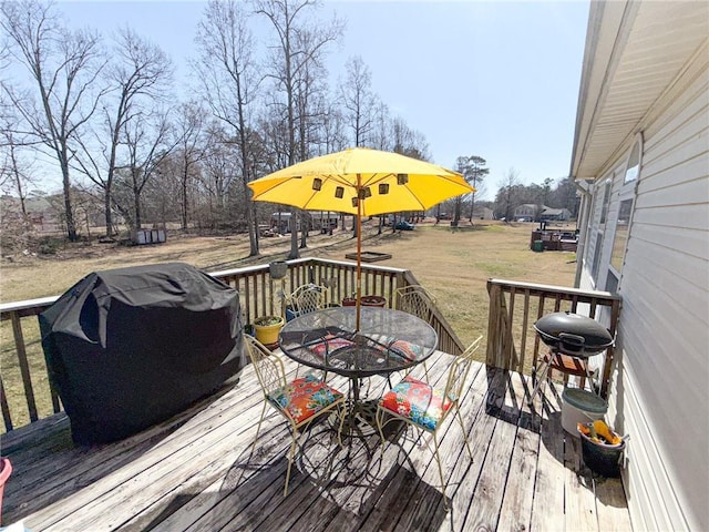wooden terrace with outdoor dining space, a lawn, and grilling area