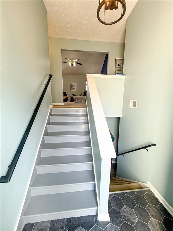 stairway with ceiling fan and a textured ceiling