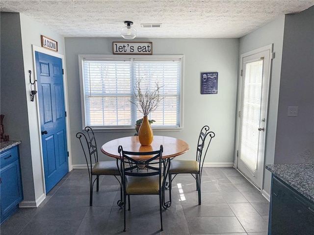 dining room featuring baseboards, visible vents, and a textured ceiling