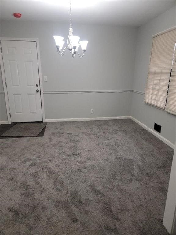 carpeted empty room with a chandelier