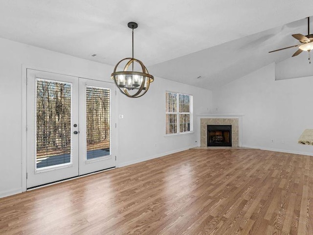 unfurnished living room with vaulted ceiling, wood finished floors, a tile fireplace, and baseboards