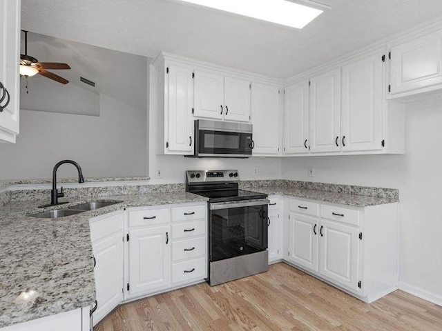 kitchen with a peninsula, electric range, a sink, light wood-style floors, and white cabinets