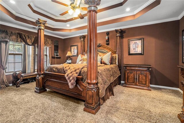 carpeted bedroom with ornate columns, a raised ceiling, ceiling fan, and crown molding