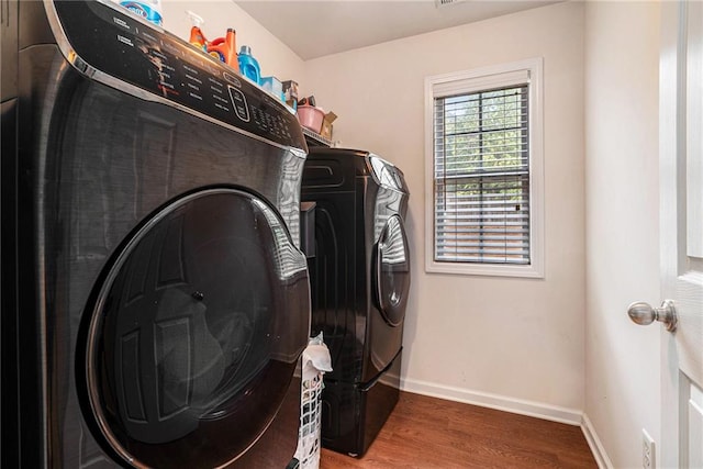 washroom with wood-type flooring and washing machine and dryer