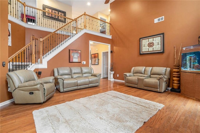 living room featuring hardwood / wood-style floors, ceiling fan, and a towering ceiling