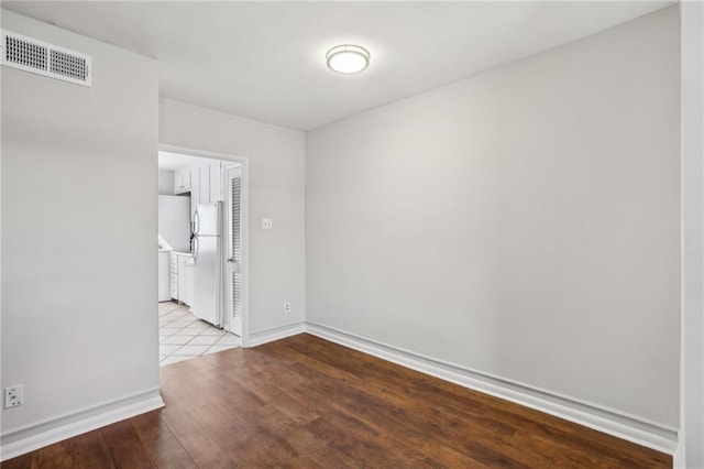 unfurnished room with baseboards, visible vents, and wood finished floors