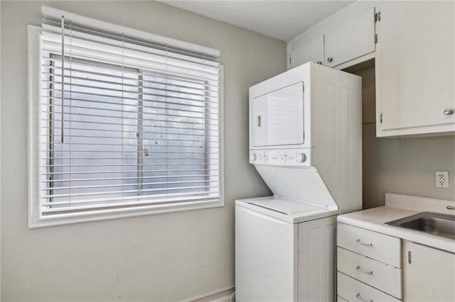 washroom featuring stacked washing maching and dryer, a sink, and cabinet space