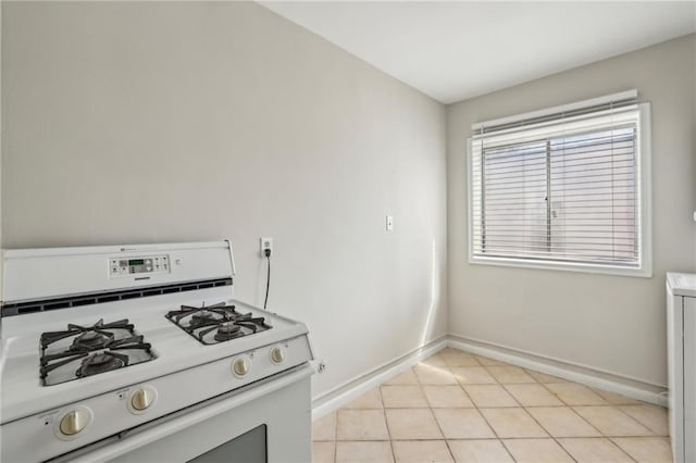 kitchen featuring white gas range oven, light tile patterned flooring, and baseboards