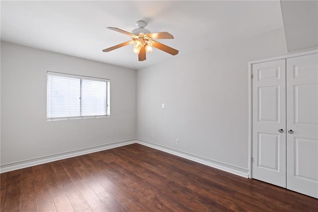 empty room with dark wood-type flooring, ceiling fan, and baseboards