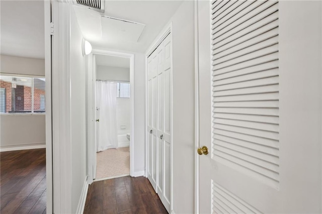 corridor with dark wood finished floors, visible vents, and baseboards