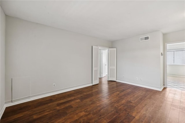 spare room with visible vents, baseboards, and wood finished floors