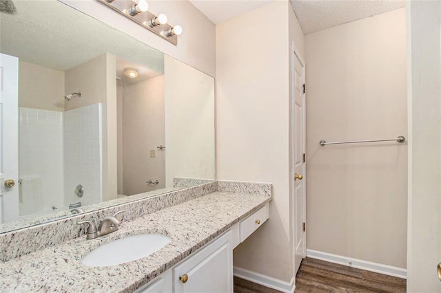 bathroom featuring a textured ceiling, baseboards, wood finished floors, and vanity