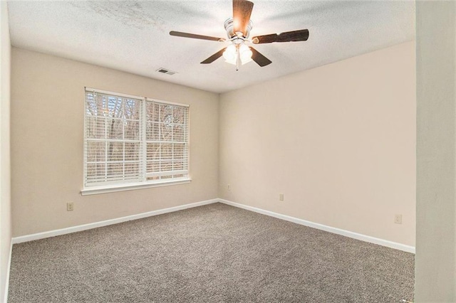 empty room featuring a textured ceiling, carpet flooring, and baseboards