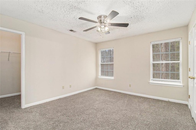 unfurnished bedroom with a walk in closet, a closet, carpet flooring, and baseboards