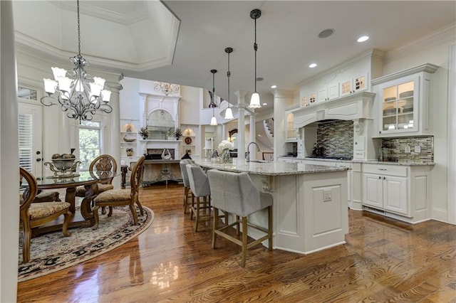 kitchen with decorative backsplash, a chandelier, glass insert cabinets, white cabinets, and dark wood-style flooring