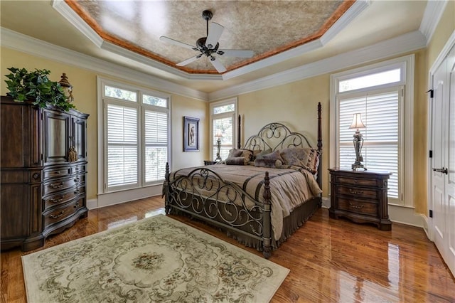 bedroom featuring ornamental molding, wood finished floors, and a tray ceiling