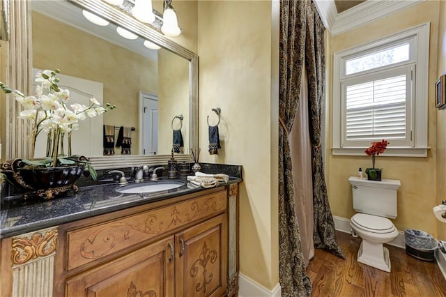 bathroom featuring wood finished floors, toilet, vanity, ornamental molding, and baseboards