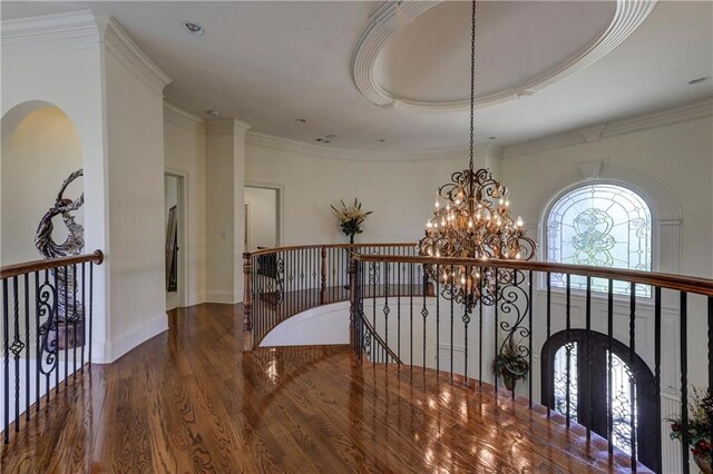 corridor with a notable chandelier, wood finished floors, an upstairs landing, arched walkways, and ornamental molding