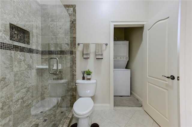 full bath featuring stacked washer / drying machine, baseboards, a tile shower, toilet, and tile patterned flooring