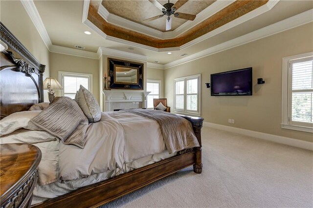 carpeted bedroom with a raised ceiling, visible vents, ornamental molding, baseboards, and ceiling fan
