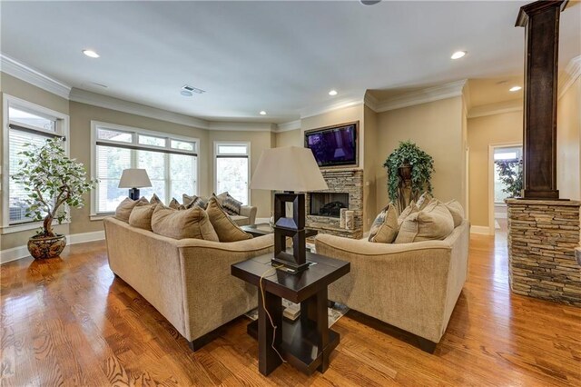 living area with baseboards, wood finished floors, and a stone fireplace
