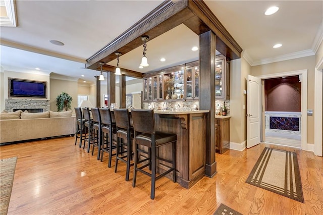 bar with wet bar, light wood finished floors, and ornamental molding